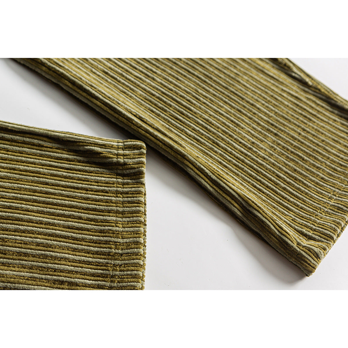 Close-up of the ribbed striped fabric and hems of olive pants.