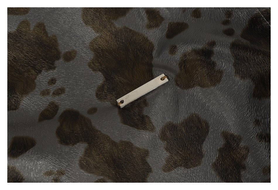 Close-up of a small metal plate on glossy gray-brown spotted garment fabric.
