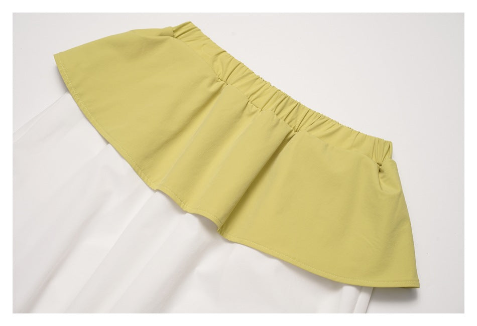 Close-up of the gathered pale yellow-green elastic waistband and layered ruffle over white pants.