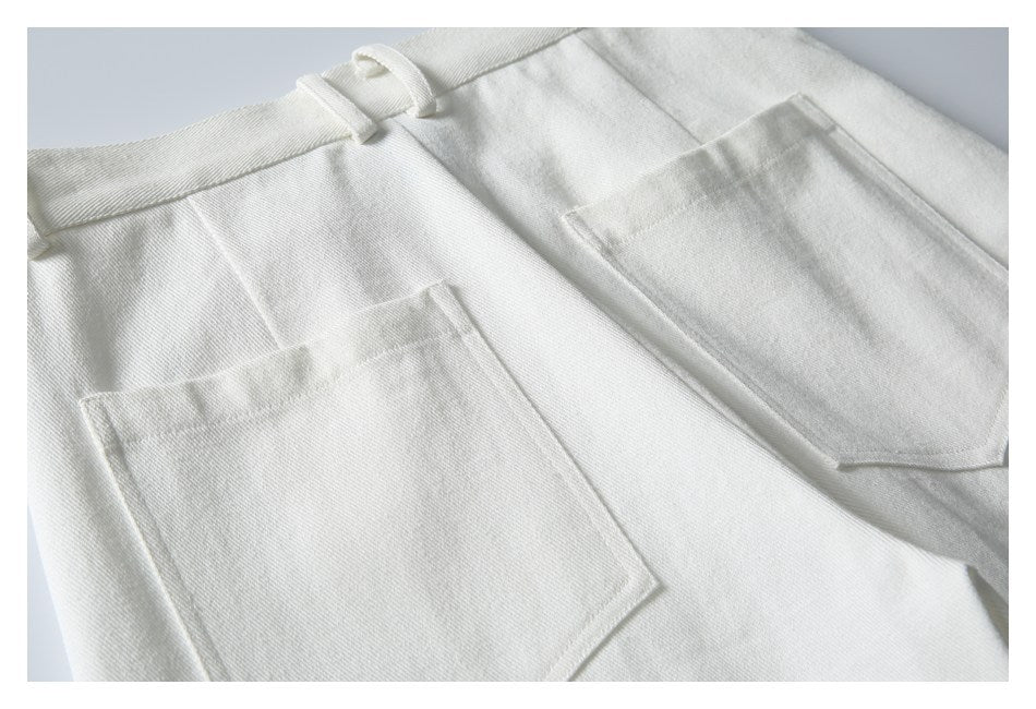 Close-up of white trousers showing the waistband, belt loops, and two large patch pockets.