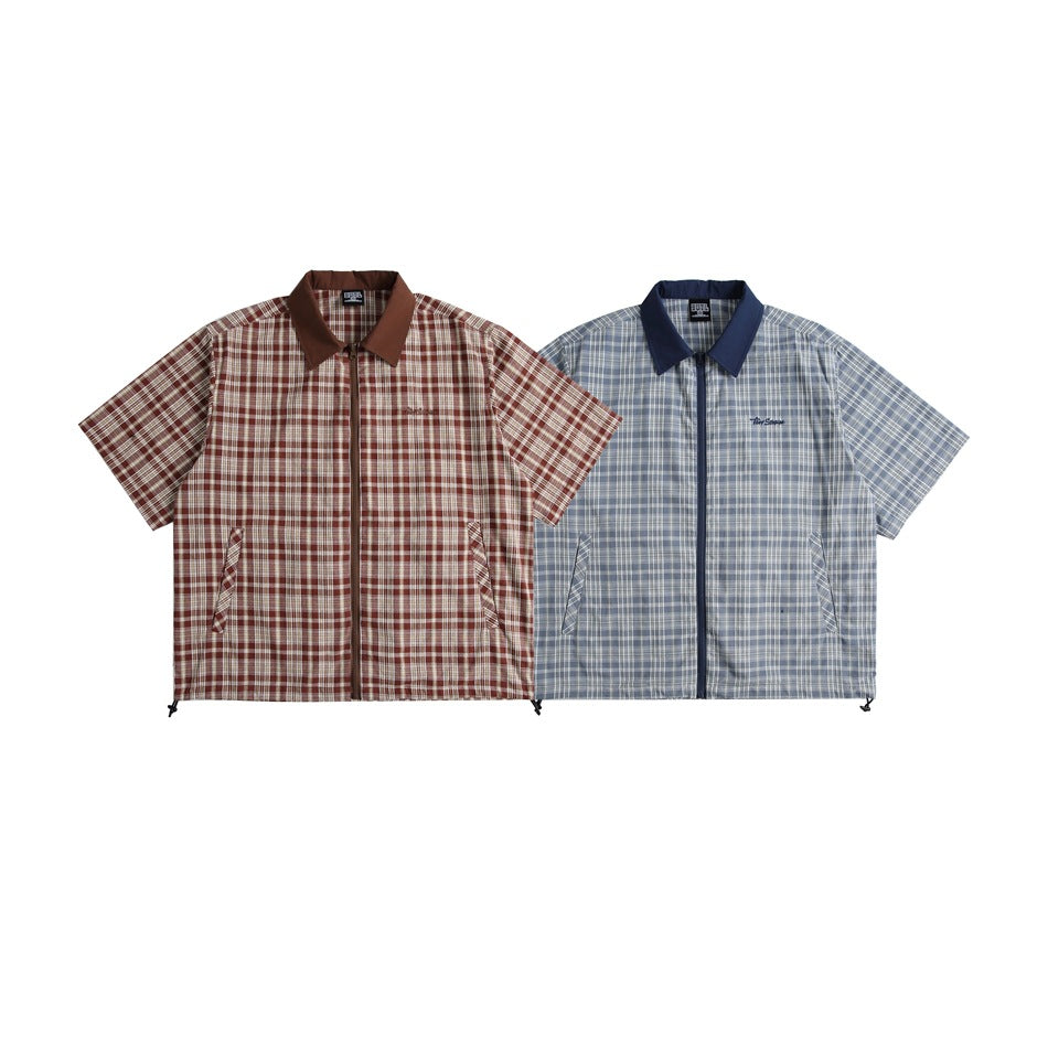 Two short-sleeve plaid zip-up shirts laid flat: one brown and cream, the other blue-gray with a navy collar.