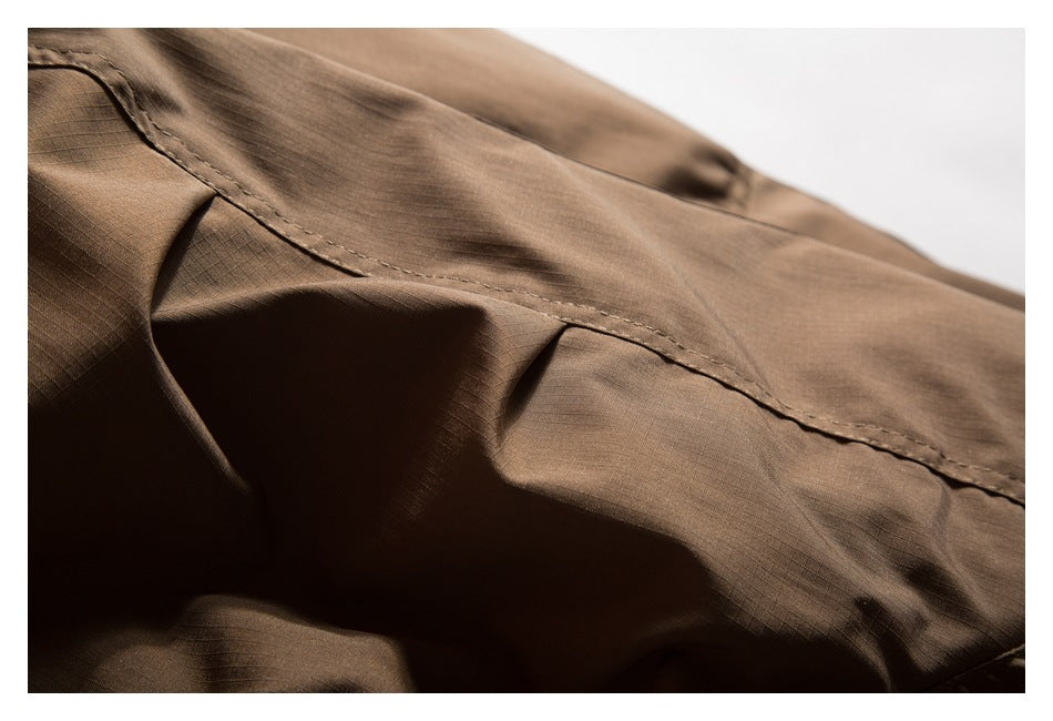 Close-up of a stitched seam and folds in brown grid-textured garment fabric.