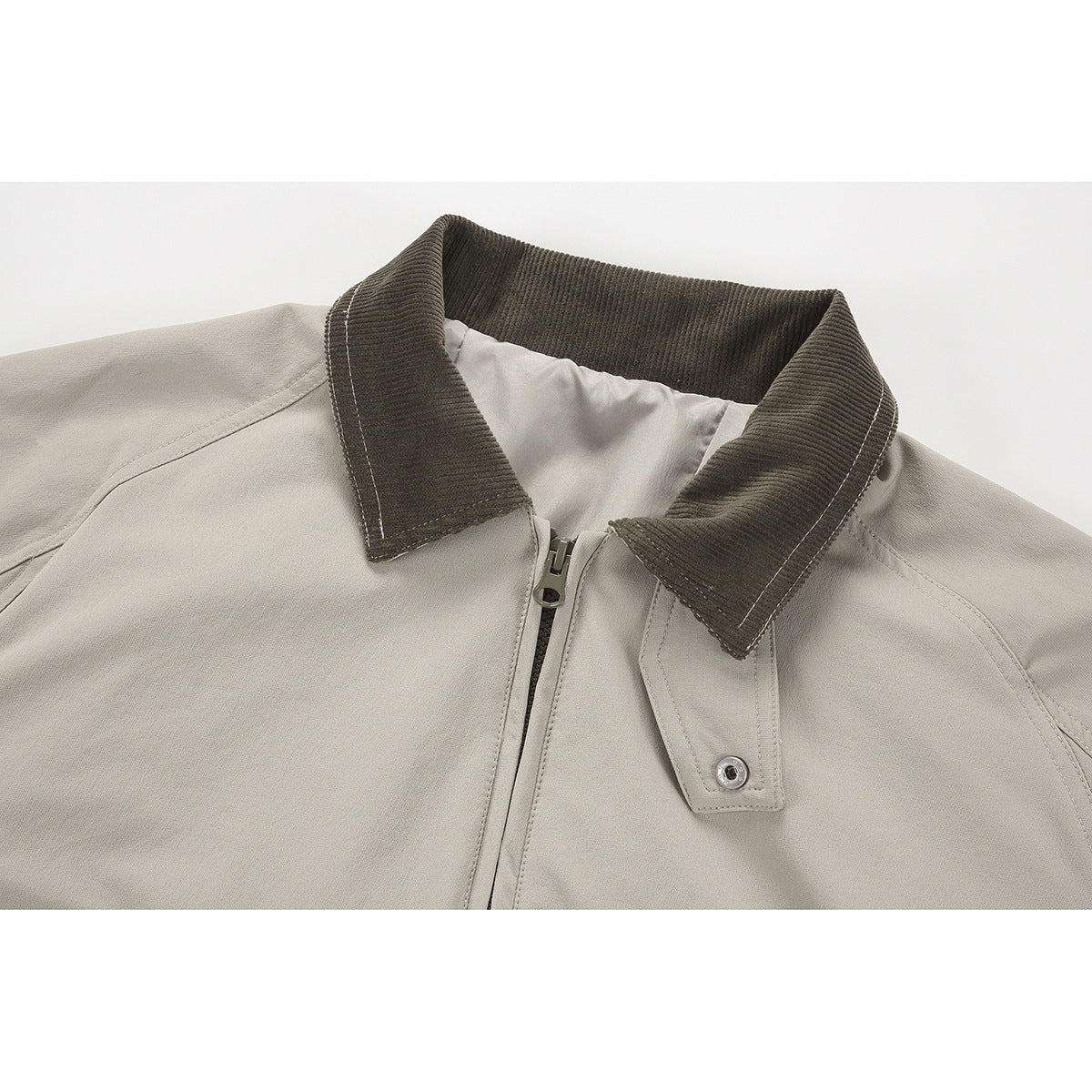 Close-up of a light taupe jacket with a dark brown corduroy collar, zipper, and snap-tab detail.