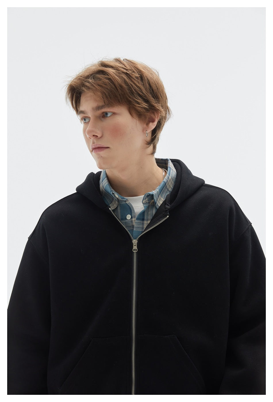 Close-up of a black zip-up hoodie showing its hood, metal zipper, and front pouch pockets.