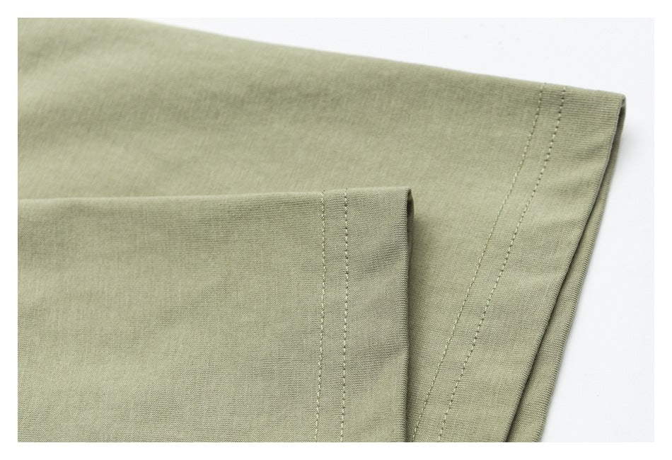 Close-up of folded olive-green garment fabric showing stitched edges and a double-stitched seam.