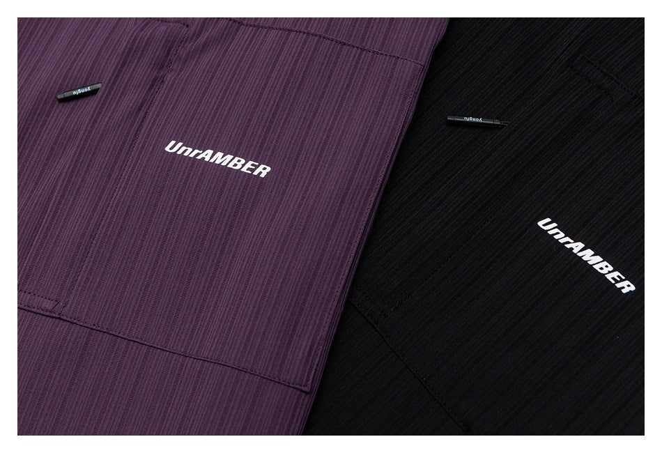 Close-up of plum-purple and black shirts with chest pockets and white UNRAMBER lettering.