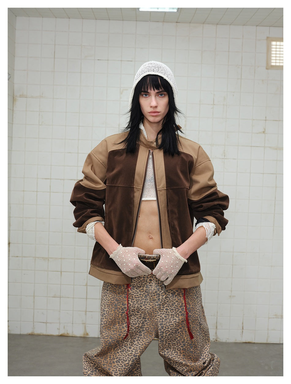 Model wearing a brown color-block zip jacket with tan panels, a white knit cap and gloves, and leopard-print trousers.