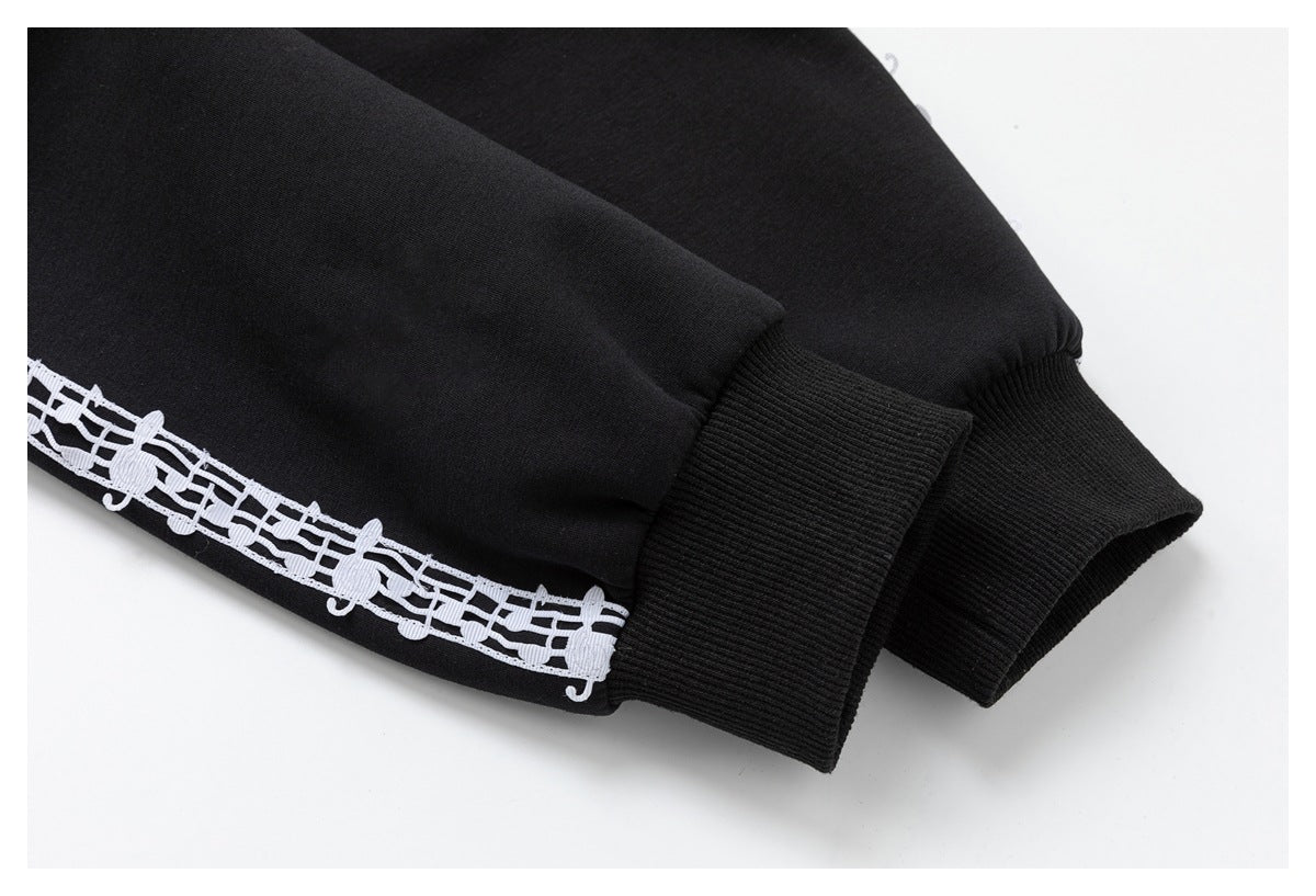 Close-up of black ribbed cuffs and a white musical-note stripe along the garment sleeve.