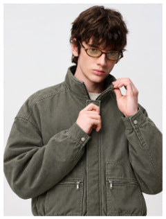 Close view of a model adjusting the collar of an olive-gray jacket with zip pockets.