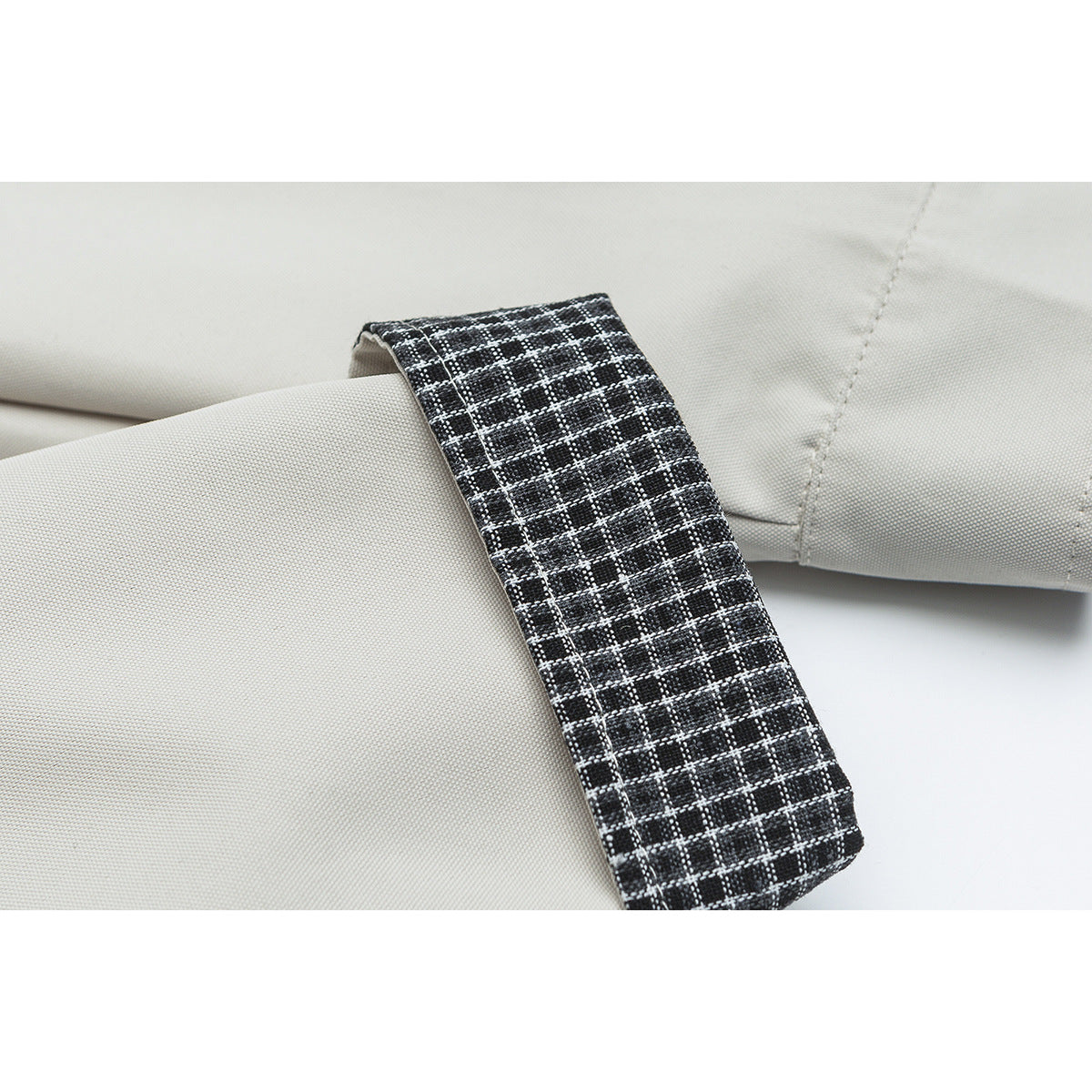 Close-up of an off-white jacket sleeve with a black-and-white checked cuff.
