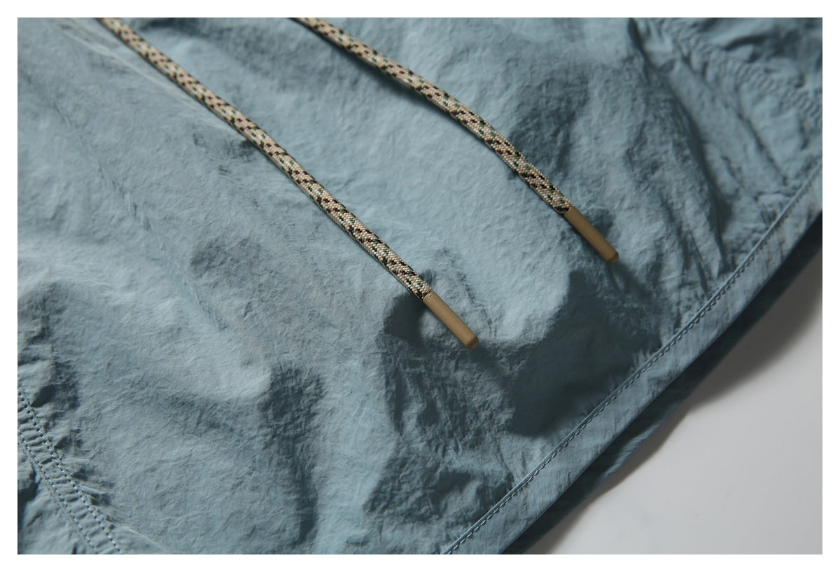 Close-up of the patterned drawstrings with tan tips against blue-gray shorts.
