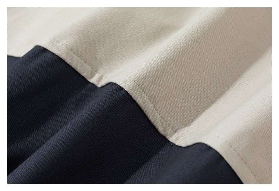Close-up of a stitched seam joining beige and dark navy fabric.
