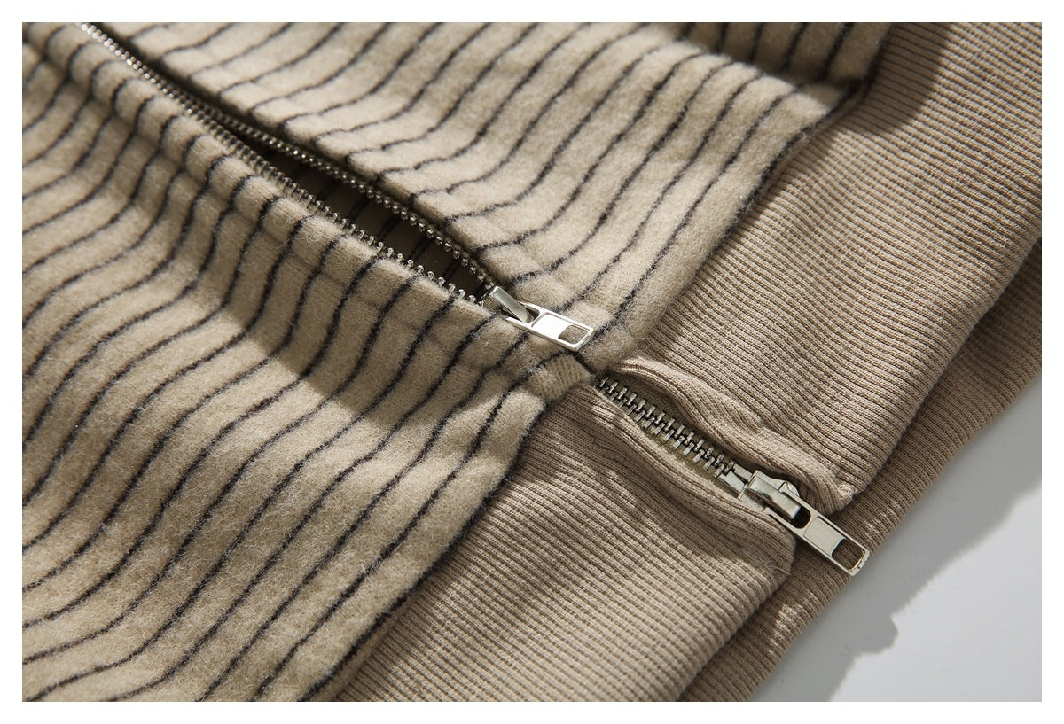 Close-up of the jacket's separated metal zipper teeth against beige striped fabric and a ribbed hem.