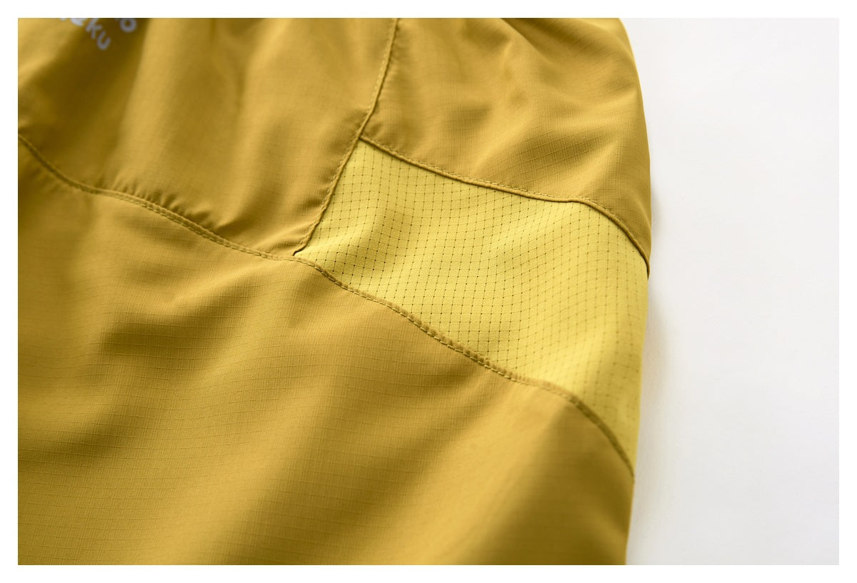 Close-up of the mustard shorts' side panel with a contrasting perforated insert and curved seams.