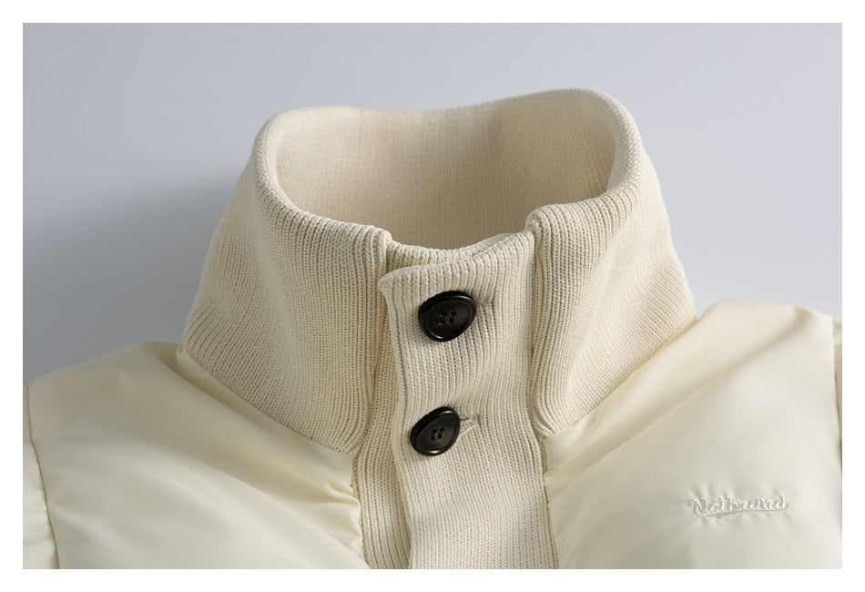 Close-up of an ivory padded jacket's tall ribbed knit collar, dark buttons, and small white embroidered lettering.