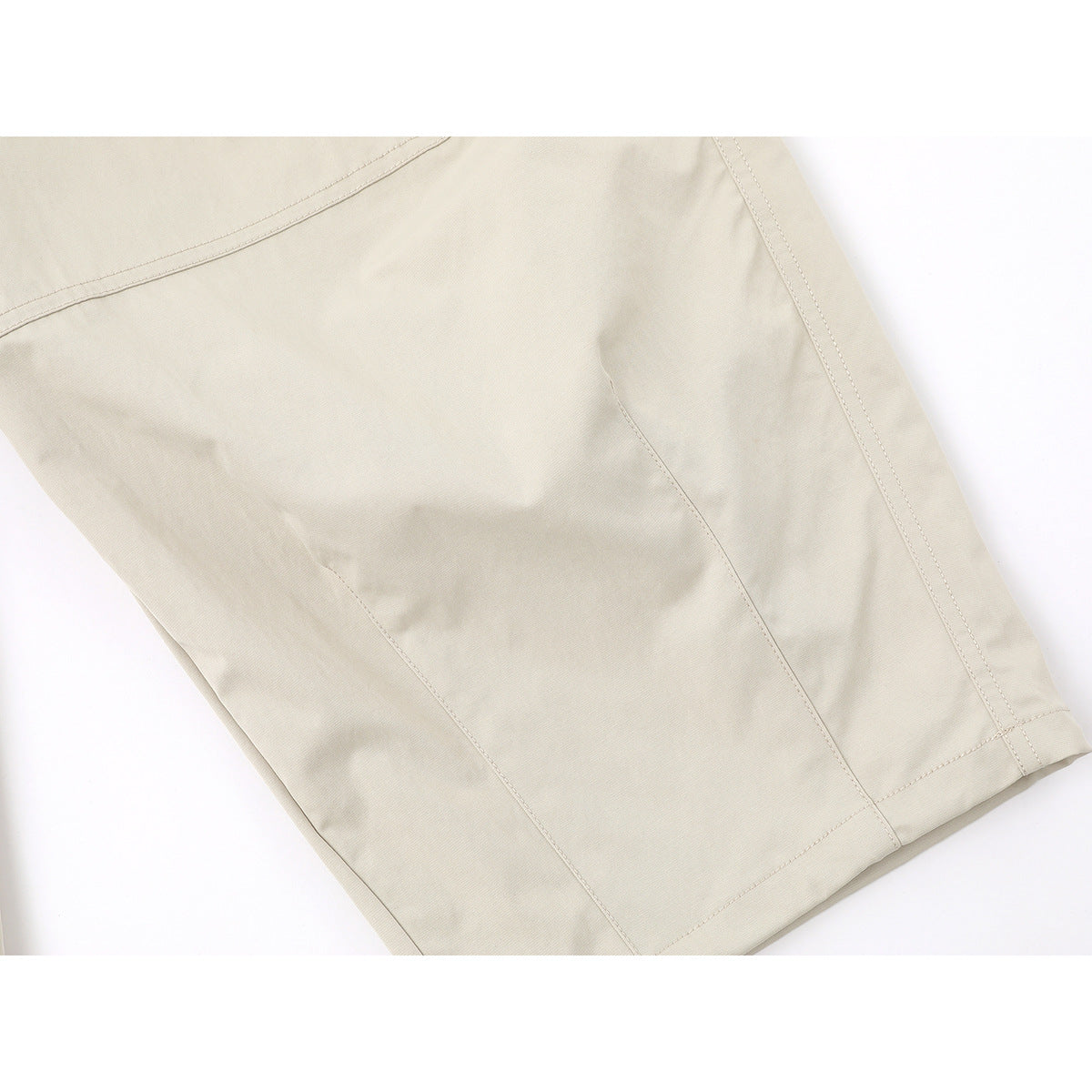 Close-up of the light beige pants leg, showing panel seams, stitching and the hem.