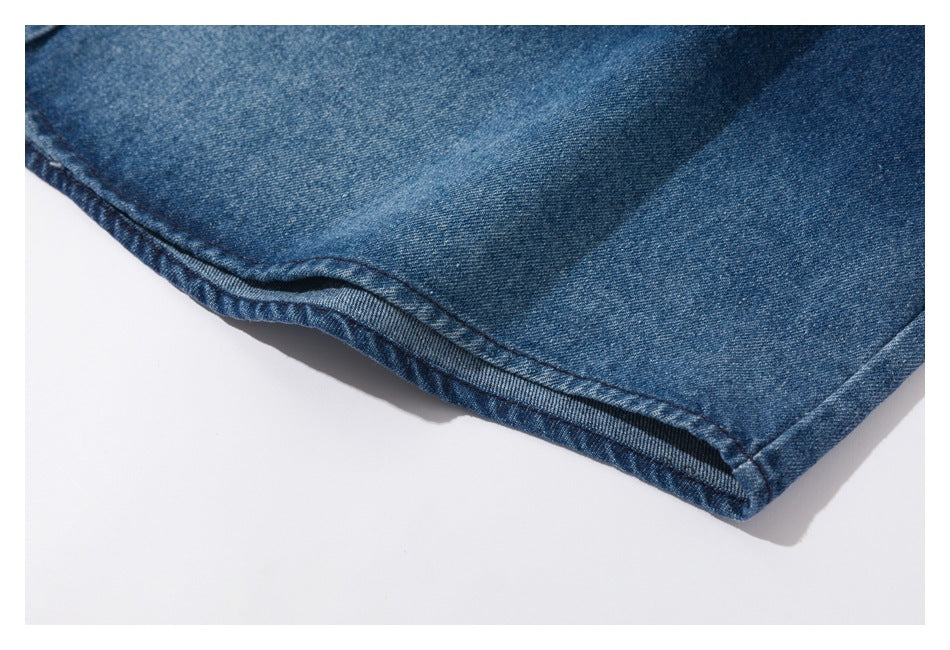 Close-up of a blue denim garment hem with visible stitching and a folded edge.