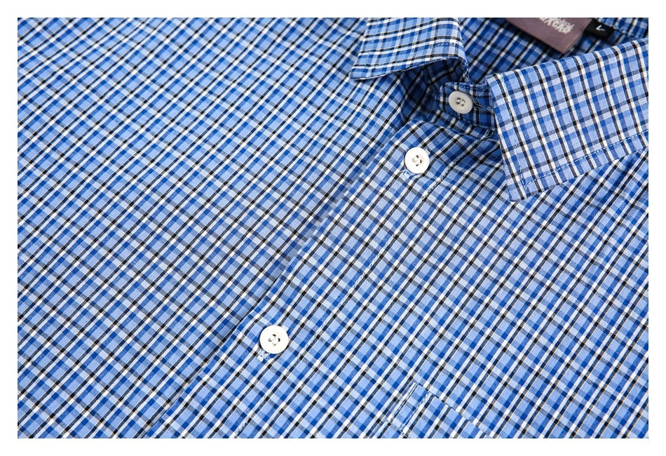 Partial flat lay of a blue, white and black plaid button-front shirt with a pointed collar and chest pocket.