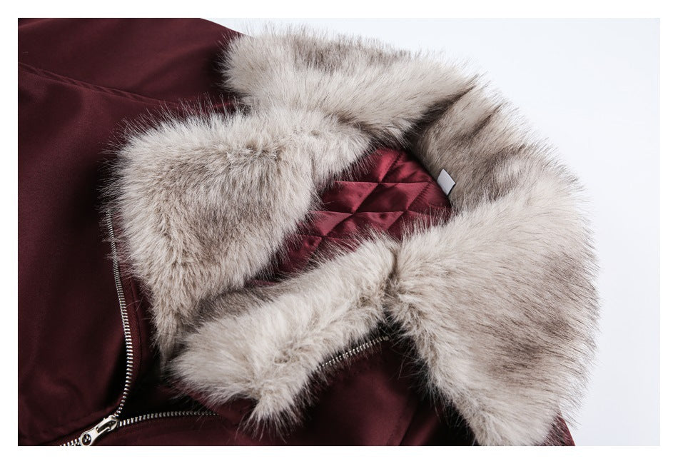 Close-up of a burgundy jacket with a wide pale gray-brown fur-trimmed hood and quilted lining.