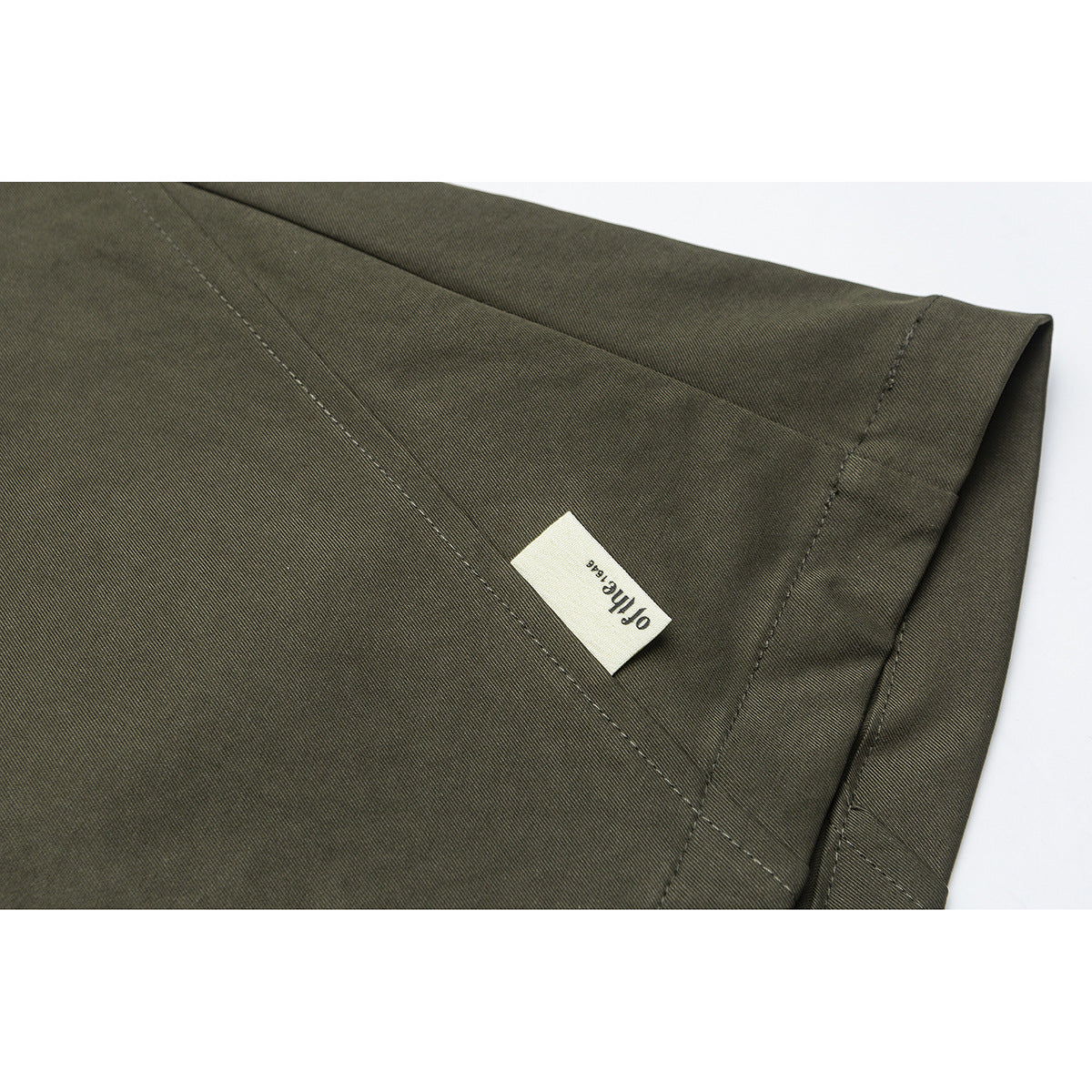 Olive trouser fabric and hem stitching with a small sewn label reading “off line.”