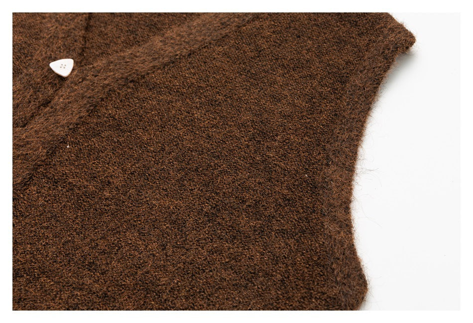 Close-up of brown fuzzy knit fabric with a white triangular button and garment edge.