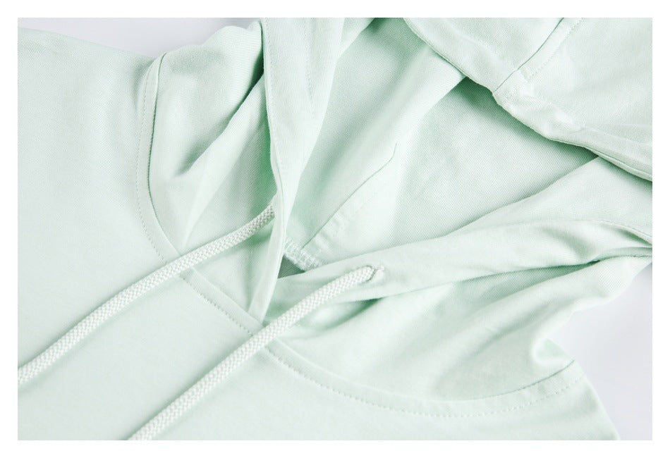 Close-up of the pale mint hoodie's neckline, showing the hood seam and white drawstrings.