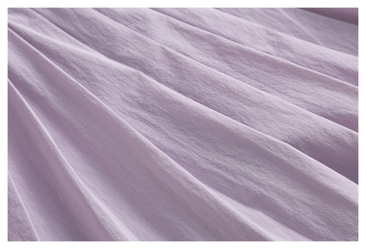 Close-up of pale lavender pleated skort fabric, highlighting the folded pleats and surface texture.
