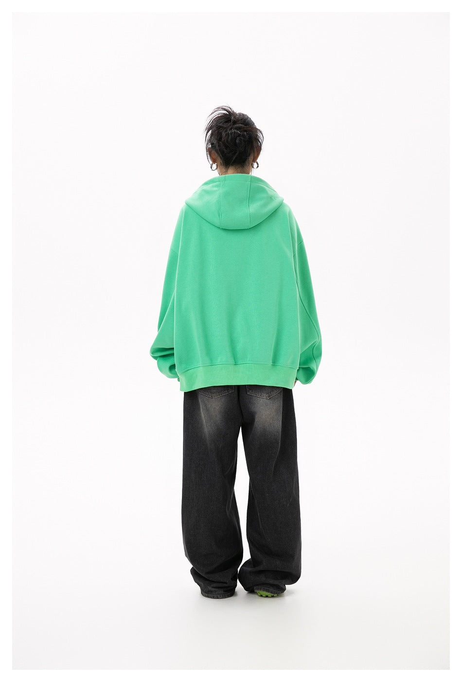 Rear view of a model wearing a plain mint-green hooded sweatshirt with ribbed cuffs and hem.