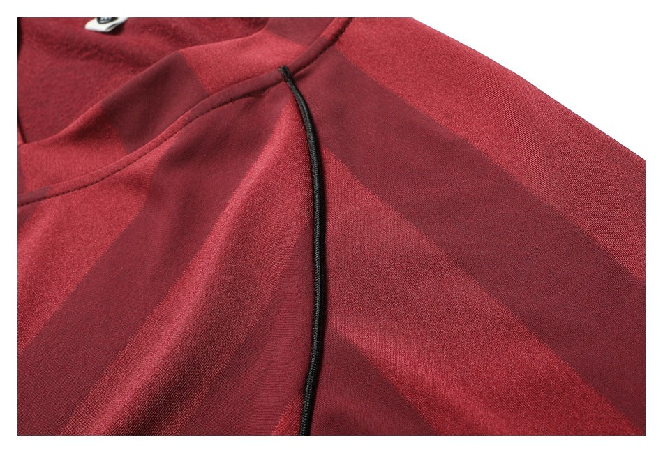 Close-up of a burgundy striped shirt neckline with black piping.