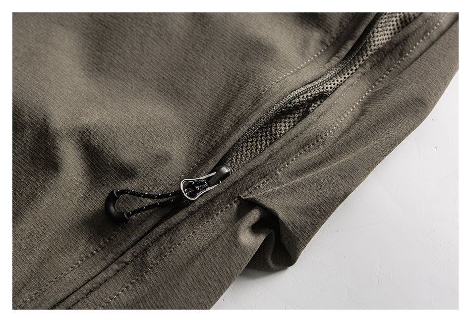 Close-up of an olive-gray garment with a black cord zipper pull and textured mesh visible beneath the opening.