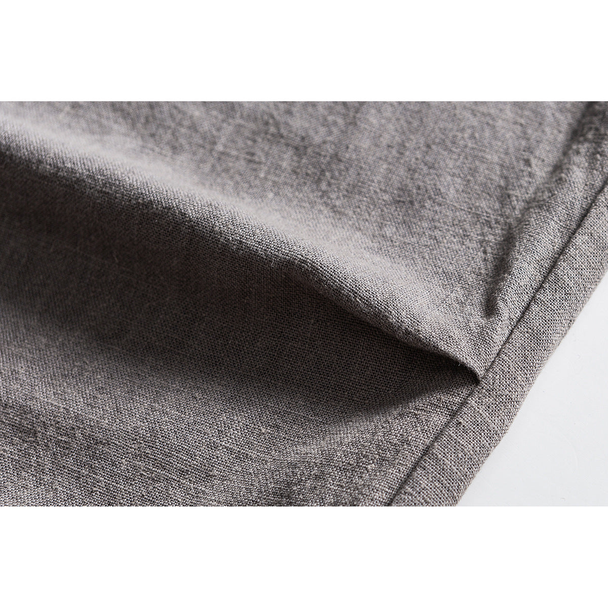 Extreme close-up of gray woven trouser fabric and a folded seam.