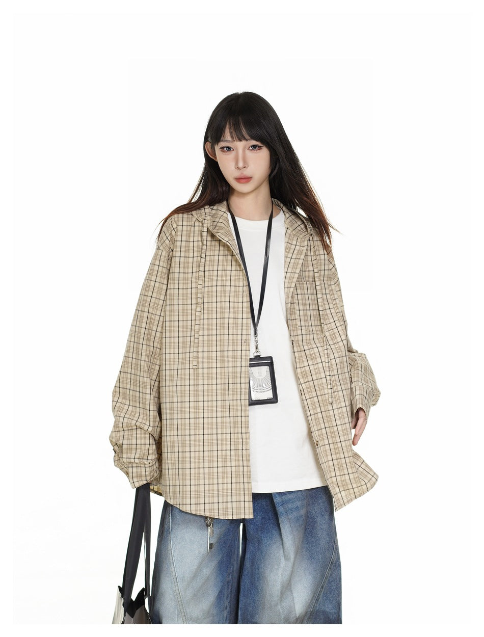 Closer front view of a model in an open beige plaid overshirt over a white top, with blue jeans.