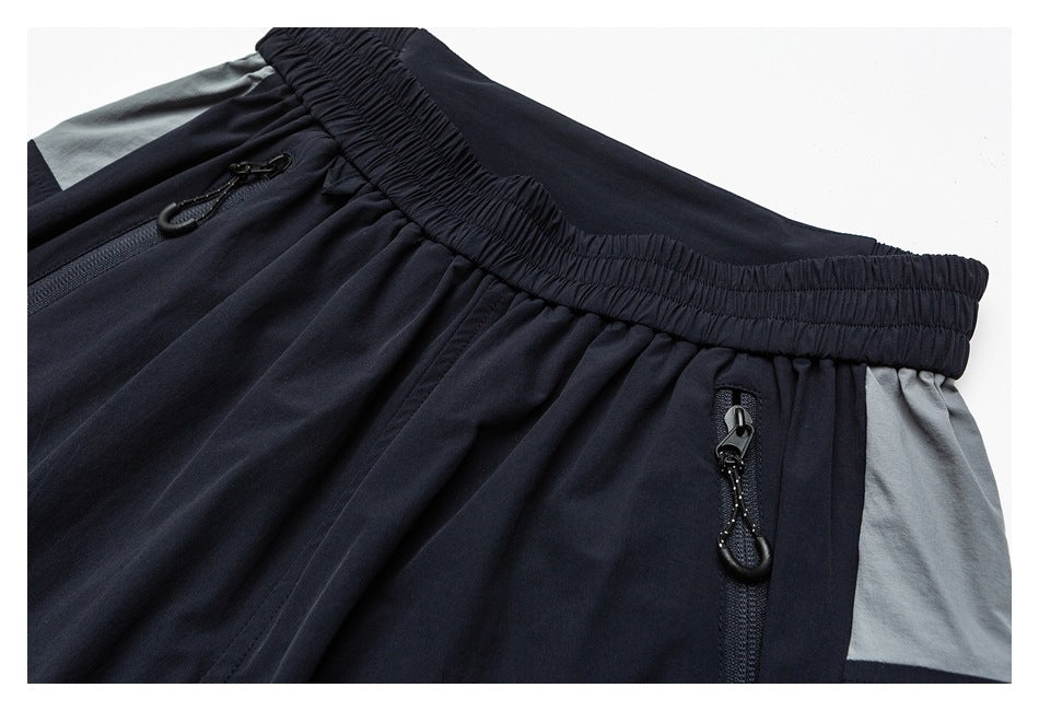 Close-up of navy pants showing the elastic waist, zip pockets and gray color-block panels.