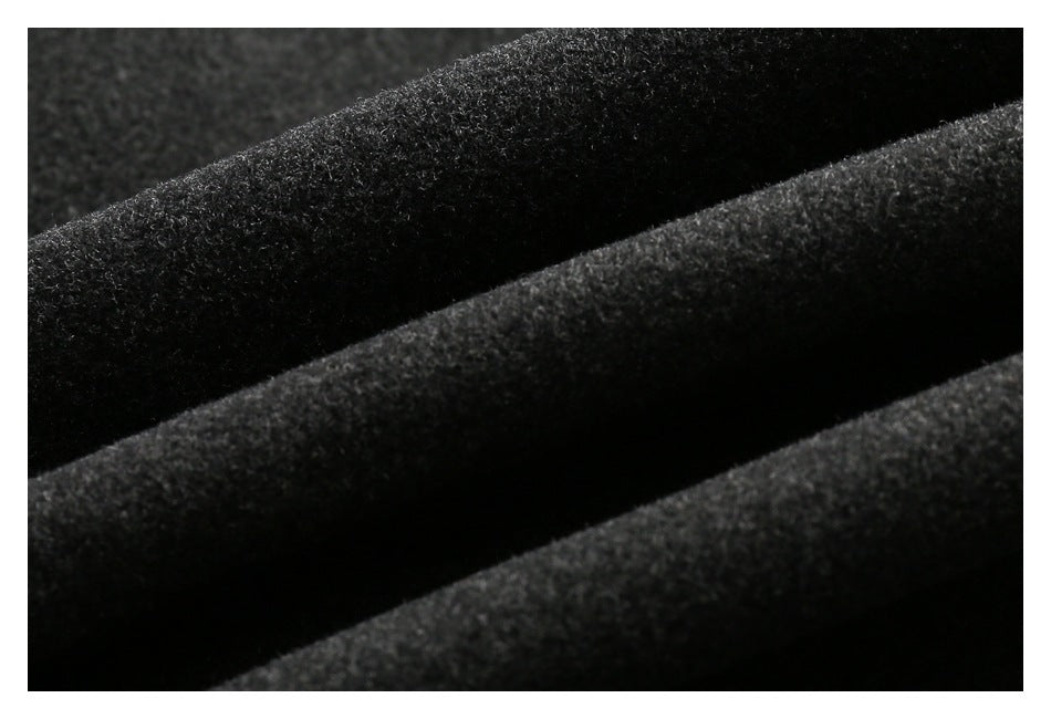 Macro view of the charcoal coat's dark, softly textured fabric in folded layers.