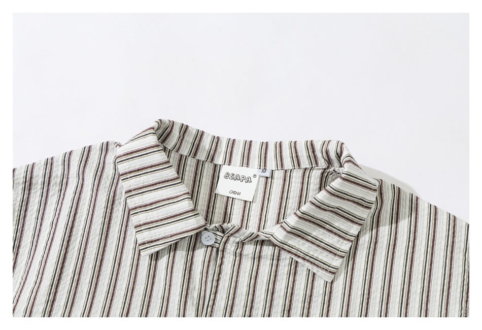 Close-up of a cream shirt collar with narrow dark stripes and a top button.