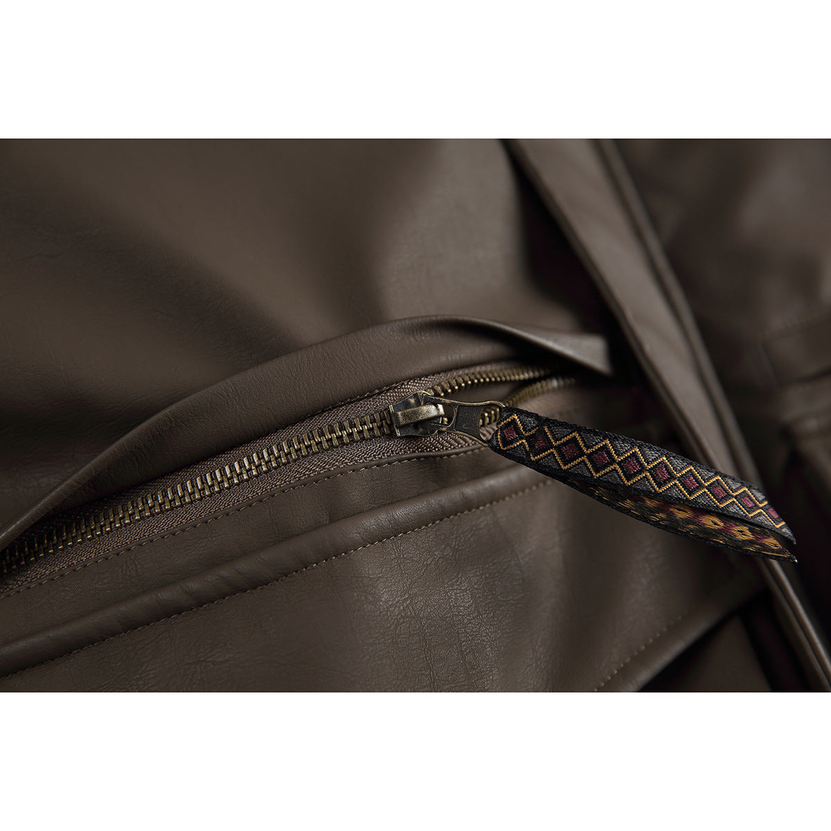 Close-up of a jacket zipper with a long, multicolored geometric-patterned pull.