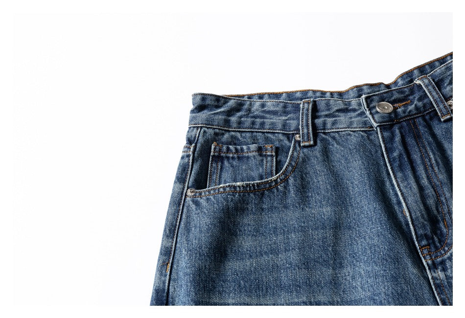 Close-up of the waistband, belt loop, coin pocket, and left front pocket of blue washed jeans.