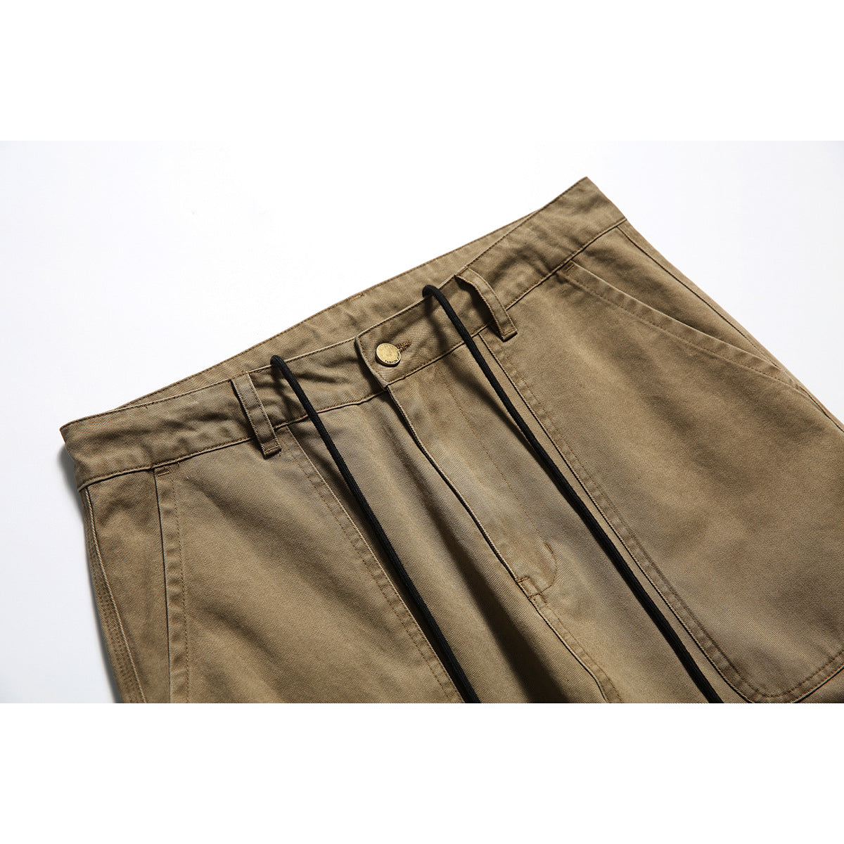 Close-up of tan utility pants showing the waistband, button, belt loops, fly, and black drawstrings.
