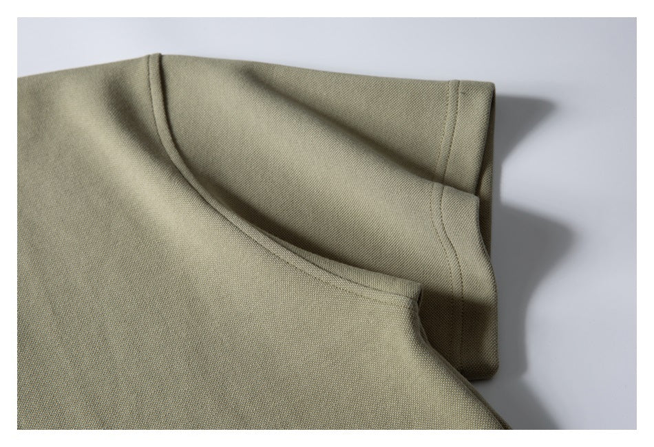 Close-up of the rounded neckline binding and stitching on a muted olive-beige garment.