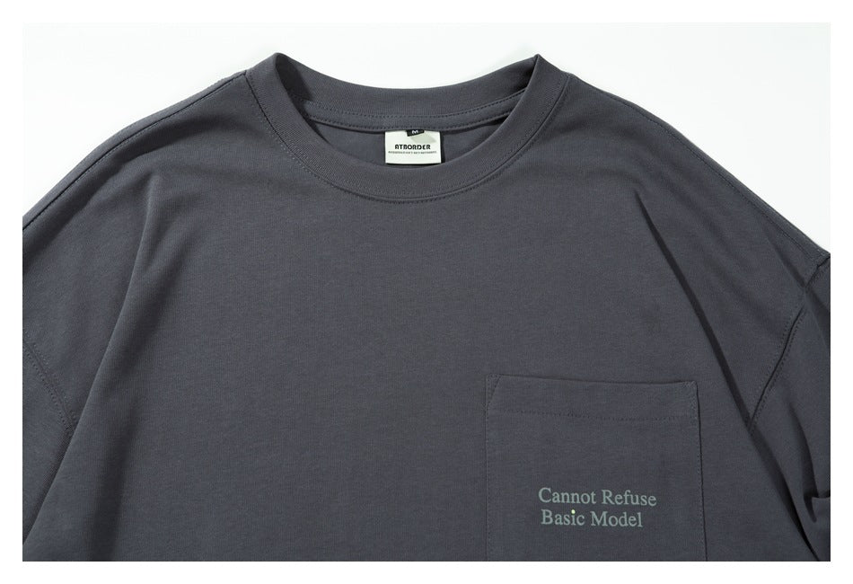 Close view of the charcoal-gray shirt's crew neck, shoulder seams, chest pocket, and English text.