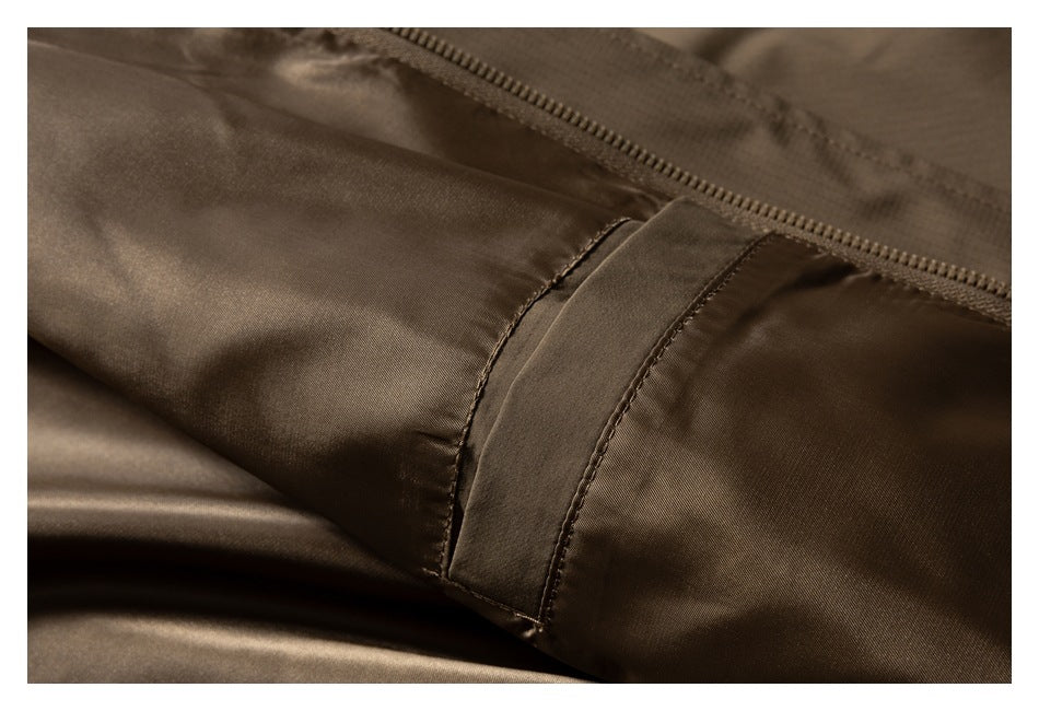 Close-up of brown jacket fabric and a stitched seam beside the zipper.