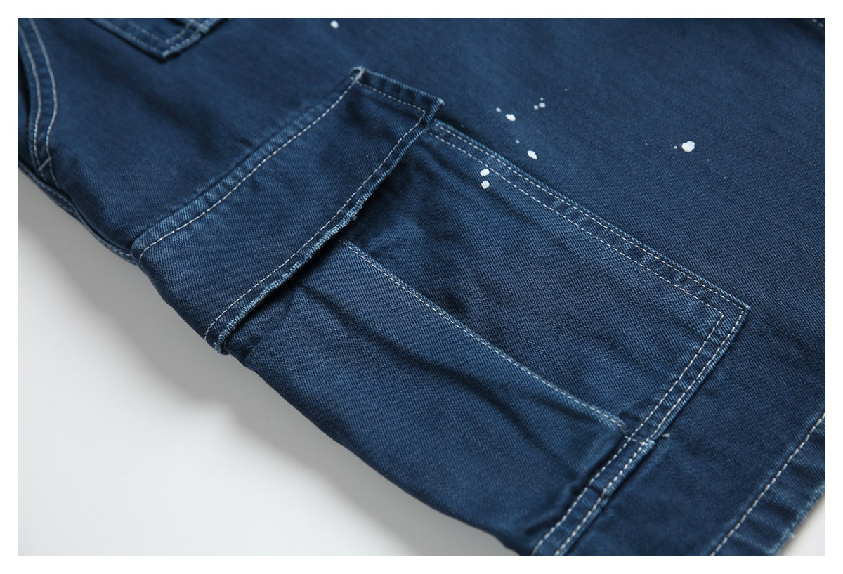 Close-up of a rectangular patch pocket on dark blue jeans with white paint-like flecks nearby.