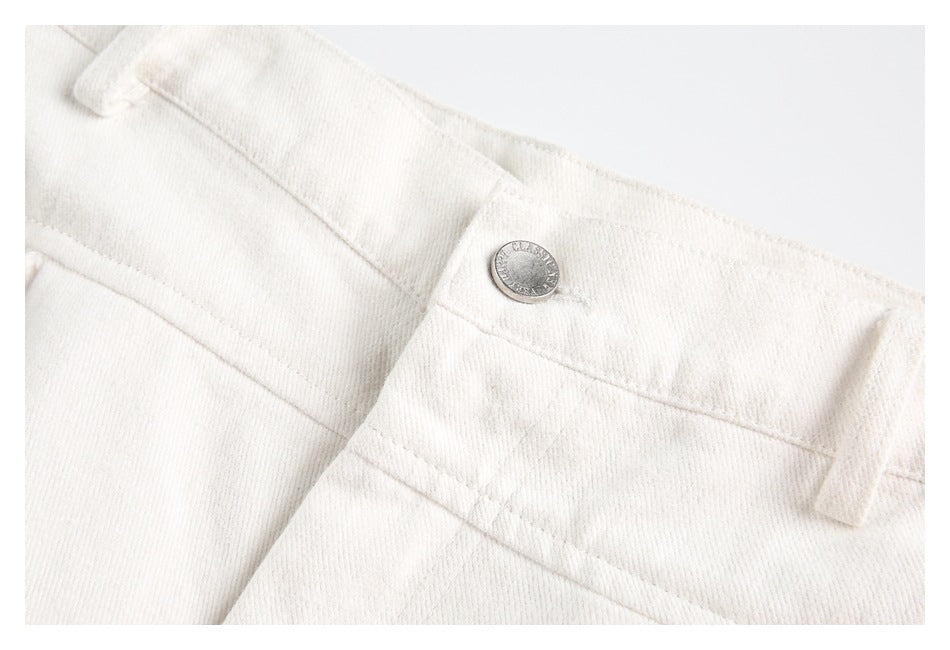 Close-up of the ivory trousers' waistband, belt loop, and silver button.