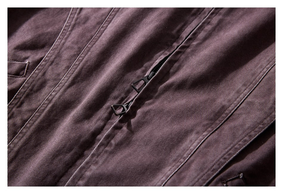 Close-up of the muted plum-brown jacket's zipper with a dark geometric pull.