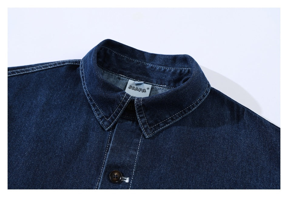 Close-up of a dark indigo denim shirt collar, neck label, and upper button.