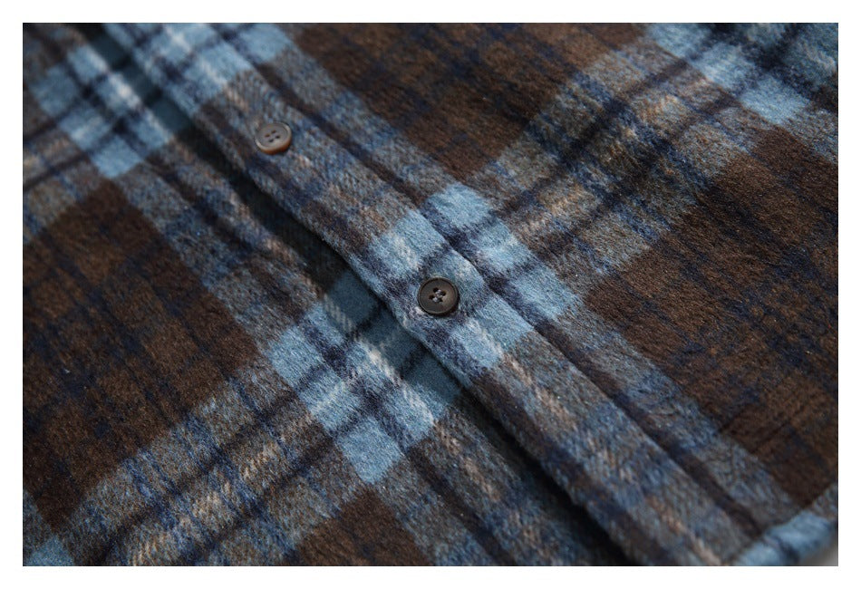Close-up of a brown and blue plaid shirt showing the fuzzy fabric and two dark buttons.