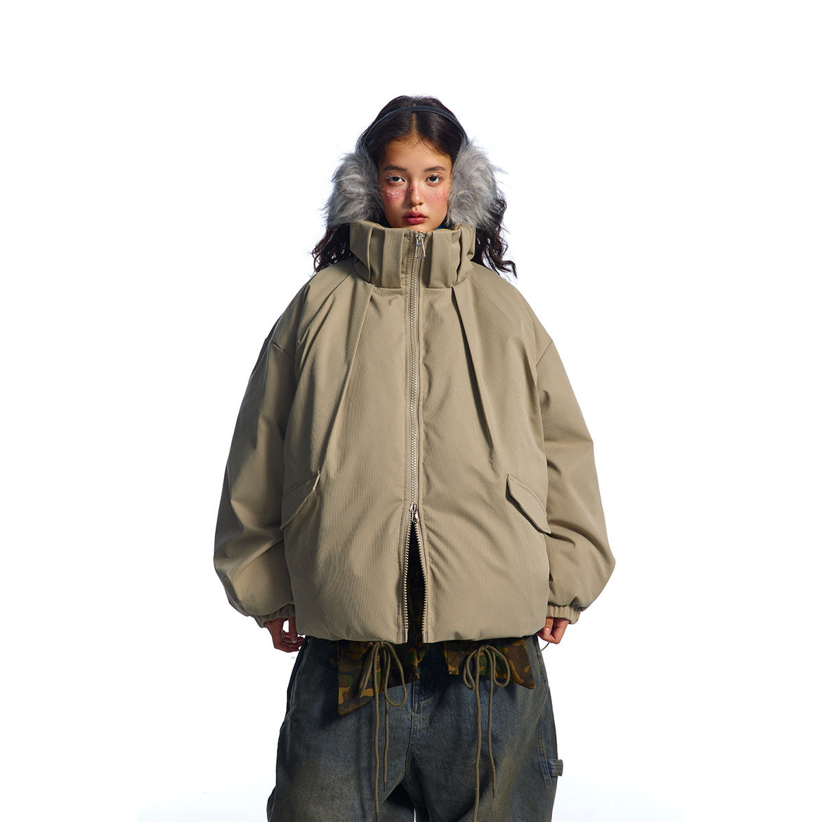 Front view of a model in a zipped taupe oversized jacket with a tall collar and flap pockets.