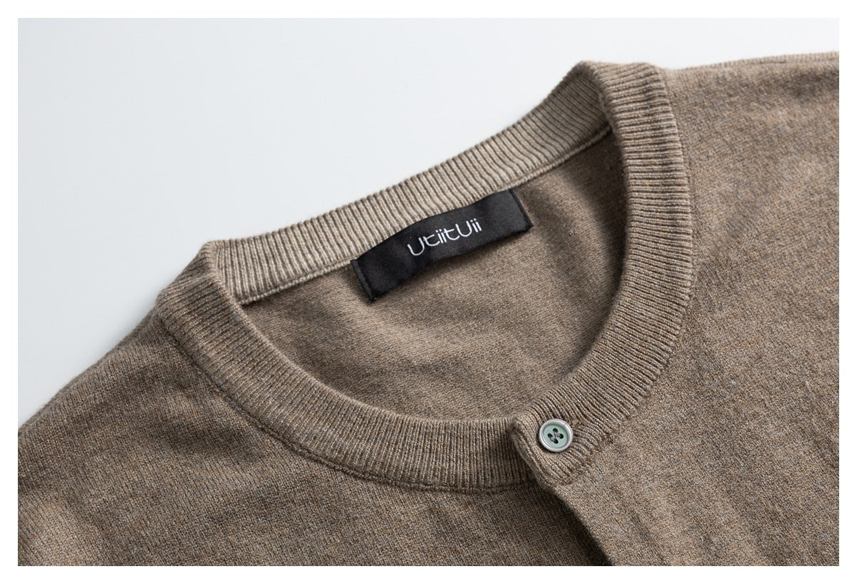 Close-up of a taupe cardigan's ribbed neckline, sewn-in label, and top button.