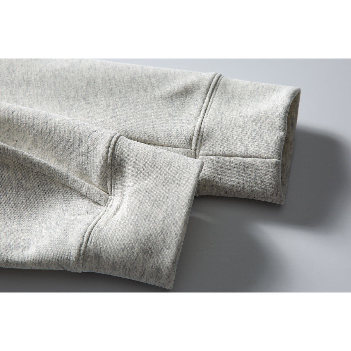 Close-up of the light gray heather sweatshirt's sleeve cuffs and seam detailing.