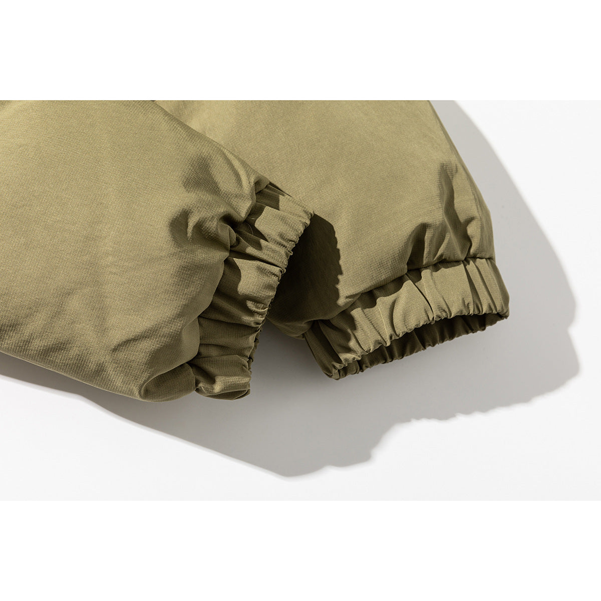 Close-up of the olive-khaki padded jacket's gathered elastic cuffs and sleeve seams.